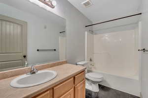Bathroom with dark tile patterned floors, vanity, and bathing tub / shower combination