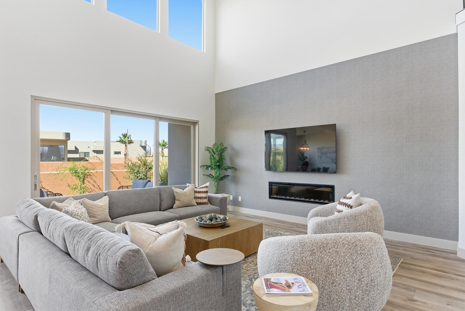 Living area featuring a glass covered fireplace, wood finished floors, a towering ceiling, and wallpapered walls