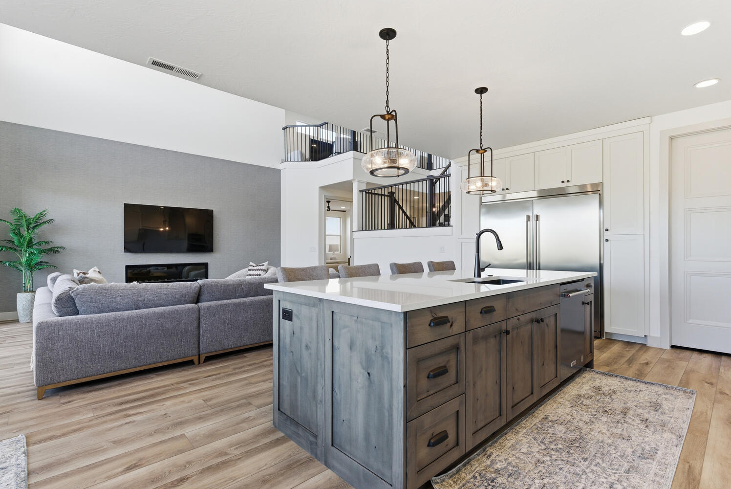 Kitchen featuring white cabinets, light wood-type flooring, pendant lighting, an island with sink, and dark brown cabinetry