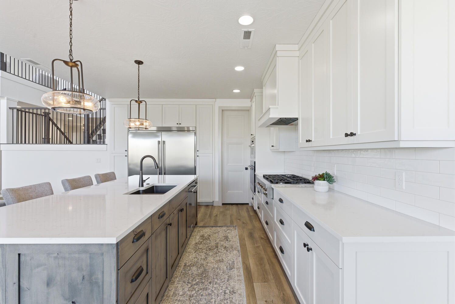 Kitchen with a kitchen bar, white cabinets, hanging light fixtures, appliances with stainless steel finishes, and dark wood-style flooring