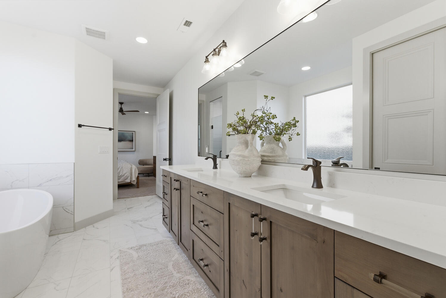Ensuite bathroom with light marble finish flooring, a freestanding bath, double vanity, recessed lighting, and a ceiling fan