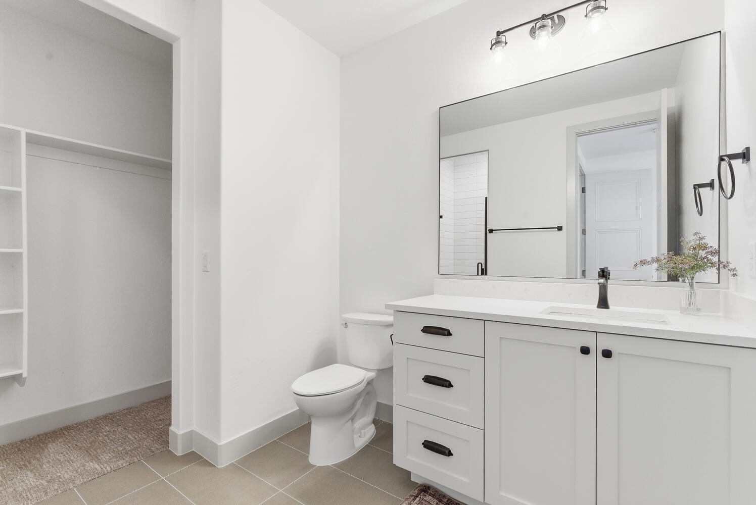 Bathroom with light tile patterned floors, vanity, and a spacious closet