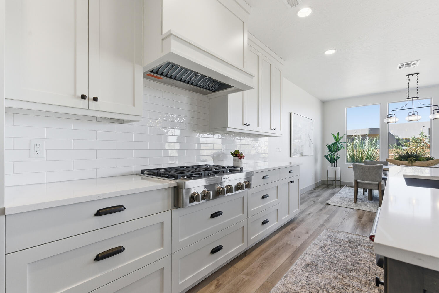 Kitchen with white cabinetry, light wood-style flooring, stainless steel gas cooktop, pendant lighting, and light stone countertops