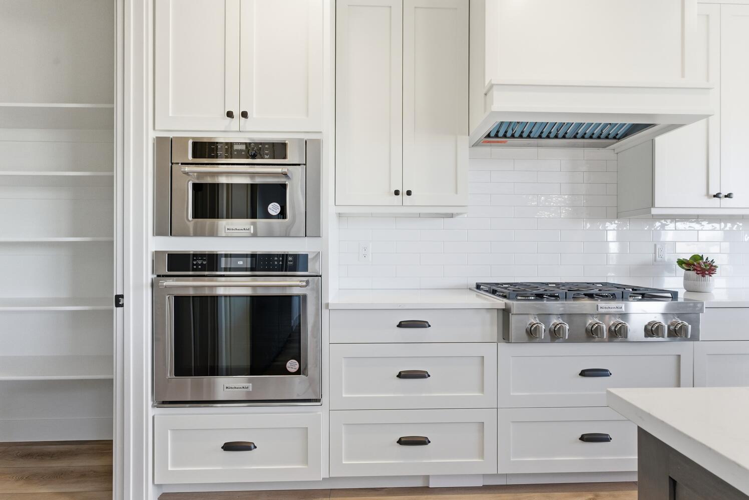 Kitchen with white cabinets, stainless steel appliances, and decorative backsplash
