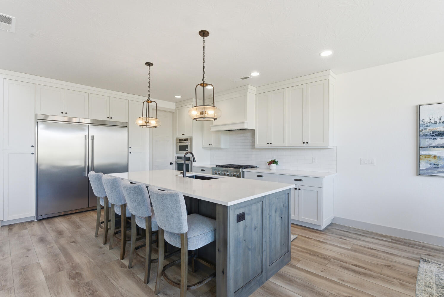 Kitchen with appliances with stainless steel finishes, white cabinets, pendant lighting, a kitchen breakfast bar, and decorative backsplash