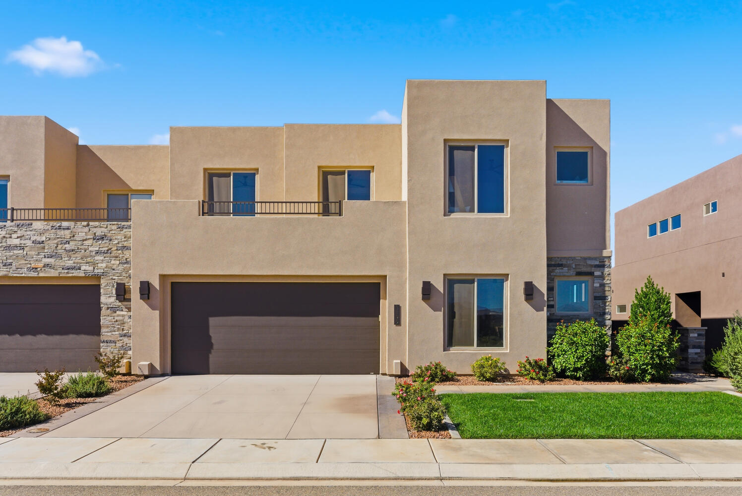 View of front facade with stone siding, stucco siding, and concrete driveway
