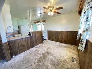 Spare room with wood walls, wainscoting, carpet, and a ceiling fan