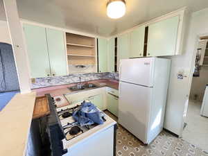 Kitchen featuring open shelves, white appliances, and green cabinetry