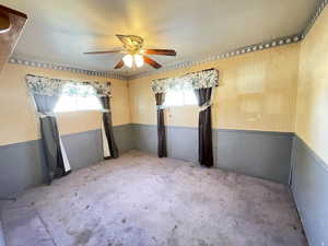 Carpeted empty room with a wainscoted wall and ceiling fan