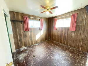 Unfurnished room with plenty of natural light, ceiling fan, and wooden walls