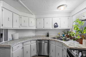 Kitchen featuring white cabinets, stainless steel dishwasher, electric range oven, light countertops, and a textured ceiling