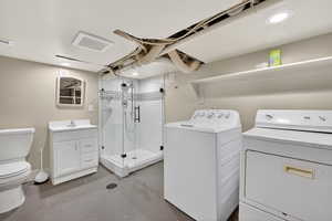 Bathroom featuring finished concrete flooring, vanity, a shower stall, and separate washer and dryer