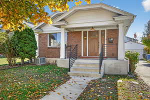 View of front of home featuring a porch, brick siding, and a front yard