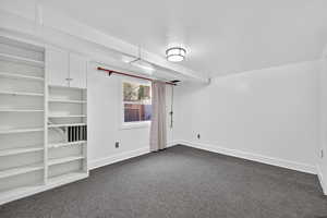 Unfurnished room featuring dark carpet and baseboards