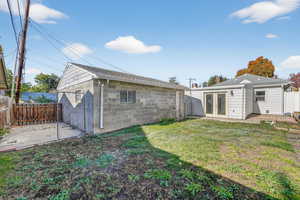 Rear view of house featuring a fenced backyard, concrete block siding, french doors, a patio area, and roof with shingles