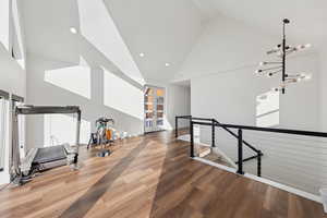 Workout room with high vaulted ceiling, light wood-style floors, recessed lighting, and french doors