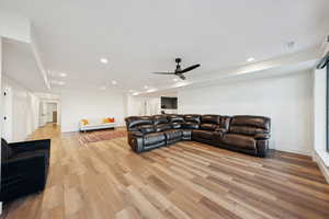 Basement apartment living room with light wood-style flooring, recessed lighting, and ceiling fan