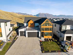View of front of property featuring a mountain view, driveway, a garage, and a large patio