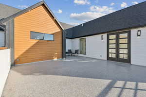 Rear view of house with roof with shingles and a patio