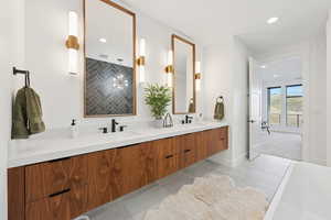 Primary en suite featuring double vanity, light tile floors, recessed lighting, and a freestanding tub