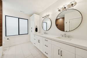 Basement apartment full bathroom with double vanity and light tile floors
