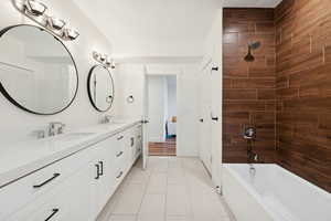 Basement apartment full bathroom with double vanity and light tile floors, and tub / shower combination