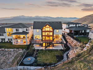 Back of house at dusk with a patio, a fenced backyard, a mountain view, and a gas fire pit