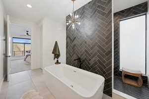 Primary en suite, soaking tub, tile walls and floors, chandelier and walk-through shower
