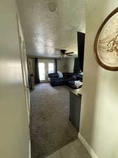 Living room featuring a textured ceiling, light colored carpet, french doors, and light wood-style flooring