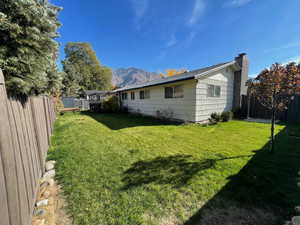 Rear view of property with a fenced backyard, a chimney, and a mountain view