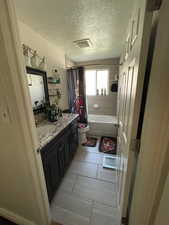 Full bath featuring vanity, shower / bathtub combination with curtain, a textured ceiling, and light tile patterned floors