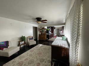 Bedroom with a textured ceiling, dark wood-style floors, and a ceiling fan