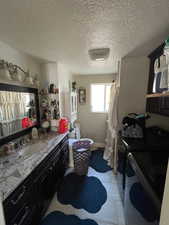 Bathroom with vanity, a textured ceiling, light tile patterned floors, and a shower with shower curtain