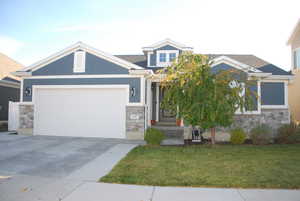 Craftsman house with stone siding, driveway, a front yard, and a garage