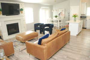 Living room with a glass covered fireplace, light wood-style floors, and lofted ceiling