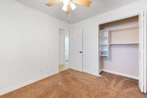 Unfurnished bedroom with light carpet, a closet, and a ceiling fan