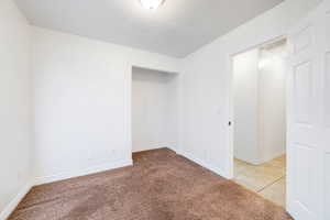 Tiled empty room with carpet flooring and baseboards