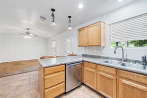 Kitchen with lofted ceiling, a peninsula, dishwasher, light tile patterned floors, and hanging light fixtures