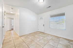 Entryway featuring light tile patterned flooring and vaulted ceiling