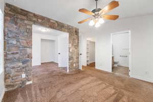 Unfurnished bedroom with light carpet, a spacious closet, connected bathroom, lofted ceiling, and a ceiling fan