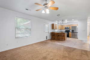 Kitchen with stainless steel appliances, light tile patterned floors, a kitchen breakfast bar, light colored carpet, and open floor plan
