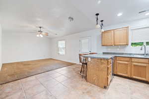 Kitchen with a peninsula, a kitchen breakfast bar, light tile patterned floors, open floor plan, and vaulted ceiling