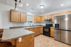 Kitchen featuring appliances with stainless steel finishes, a breakfast bar area, a peninsula, pendant lighting, and recessed lighting