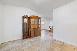 Unfurnished room featuring light tile patterned floors and lofted ceiling
