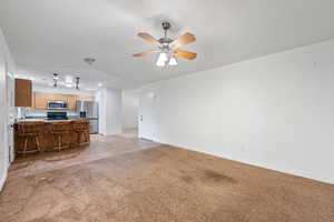 Unfurnished living room featuring light tile patterned floors, light carpet, lofted ceiling, and ceiling fan