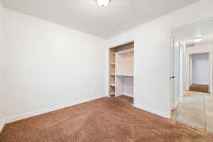 Unfurnished bedroom featuring light colored carpet, a spacious closet, and light tile patterned floors