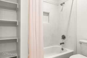 Bathroom with shower / bath combination with curtain and toilet