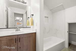 Bathroom with vanity, shower / bathtub combination, ceiling fan, and a closet