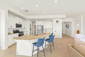 Kitchen featuring tasteful backsplash, a breakfast bar area, white cabinetry, recessed lighting, and appliances with stainless steel finishes