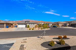 View of asphalt street featuring a mountain view, a residential view, and sidewalks